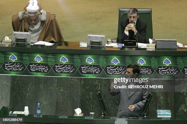 Iranian President Mahmud Ahmadinejad addresses the parliament as Parliament Speaker Gholam Ali Haddad Adel listens and his deputy Mussa Ghorbani sets...
