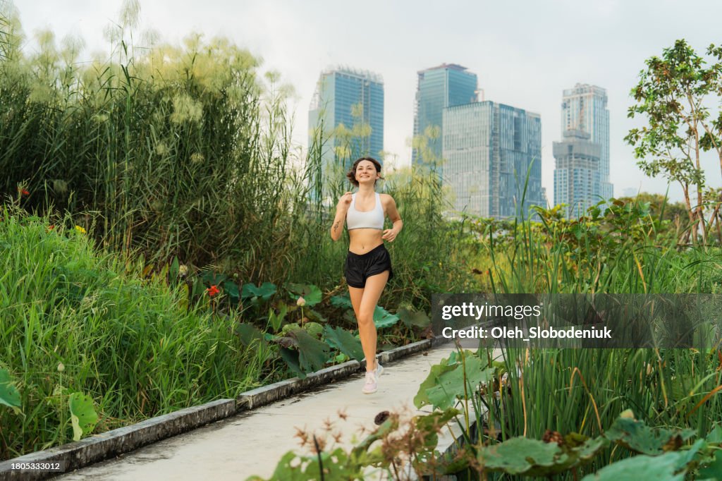 Mujer corriendo a través del exuberante follaje en el centro de la gran ciudad