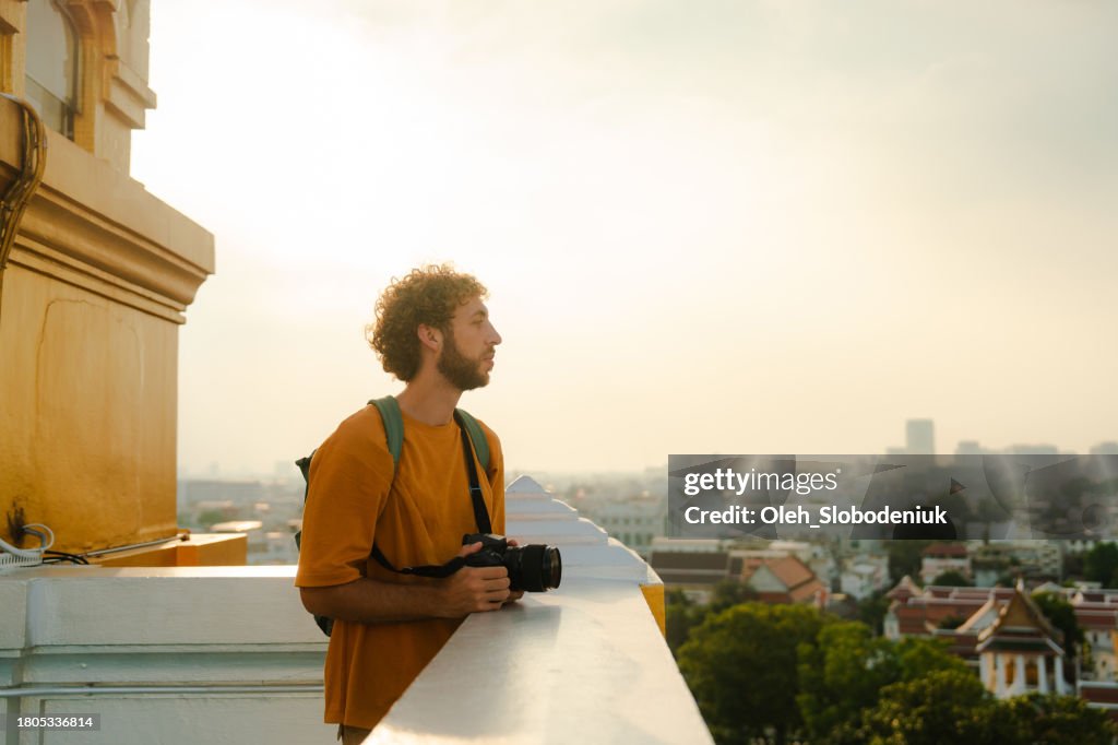 Man photographing Bangkok cityscape from viewpoint in Wat Saket