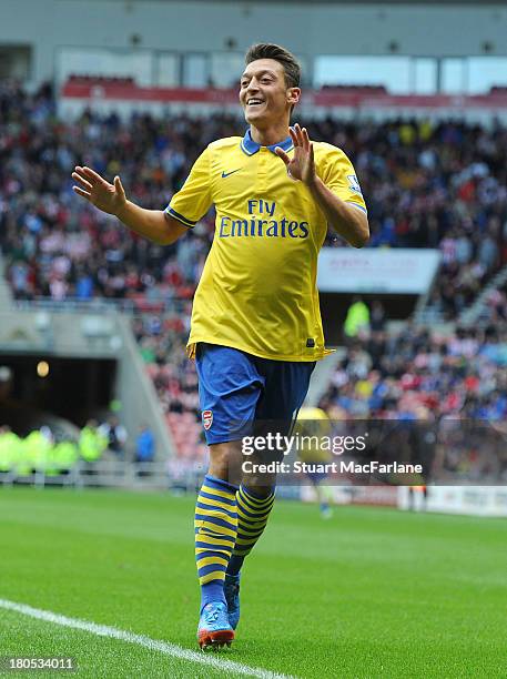 Mesut Oezil celebrates the 1st Arsenal goal scored by Olivier Giroud during the match at Stadium of Light on September 14, 2013 in Sunderland,...