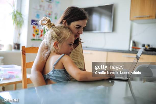 maternal multitasking: middle-aged pregnant mom working from home with kid. - crouler sous le travail photos et images de collection