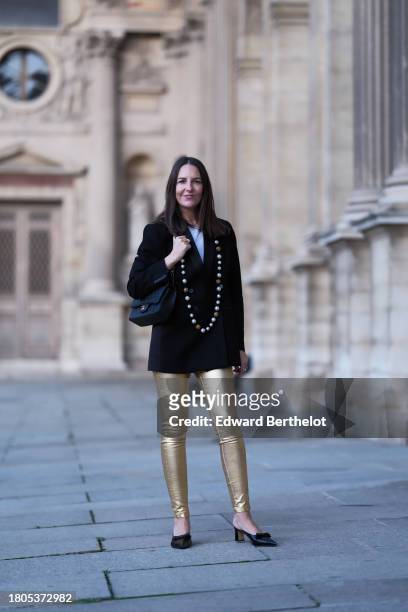 Alba Garavito Torre wears a white t-shirt from Zara, gold skinny pants from Zara, a black oversized blazer jacket from Munthe, black mules shoes from...