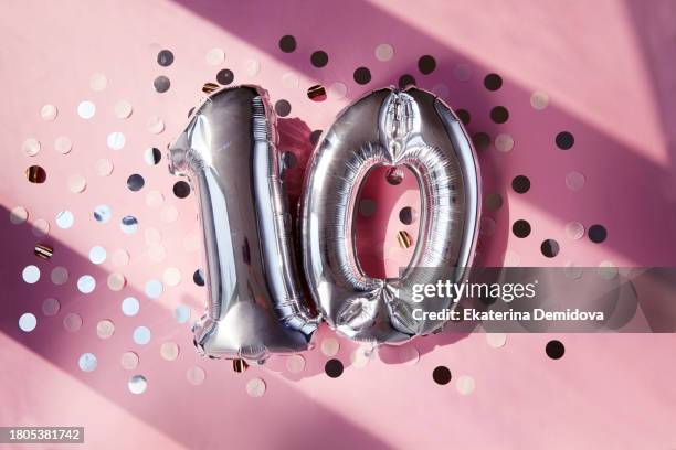 silver numbers 10 ten years balloons in sunlight pink background - 10 years stock-fotos und bilder