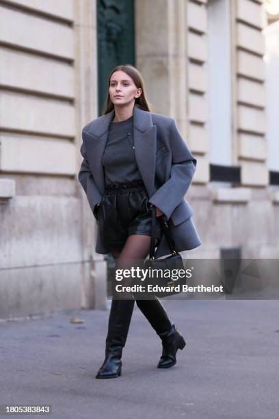 Diane Batoukina wears gray Miu Miu sweaters , a gray Miu Miu oversized jacket, Zara black tights, a black leather Fendi bag, leather knee-high boots...