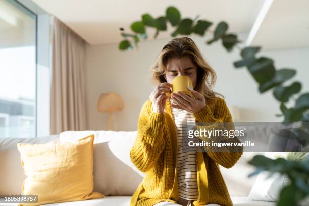 tired woman taking a break with cup of tea in the living room - hot arab women stock-fotos und bilder