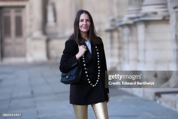 Alba Garavito Torre wears a white t-shirt from Zara, gold skinny pants from Zara, a black oversized blazer jacket from Munthe, a black Timeless...