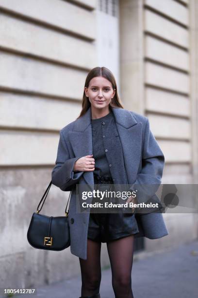 Diane Batoukina wears gray Miu Miu sweaters , a gray Miu Miu oversized jacket, Zara black tights, a black leather Fendi bag, black leather shorts...