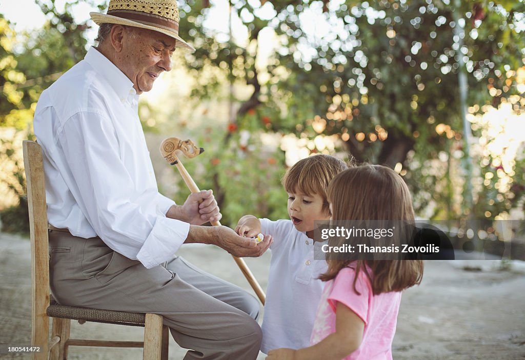 Grandfather gives candy to his grand children