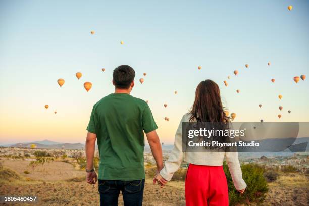 tourists enjoy watching hot air balloons flying in the sky during their vacations and enjoy the holiday and the view - verliefd worden stockfoto's en -beelden