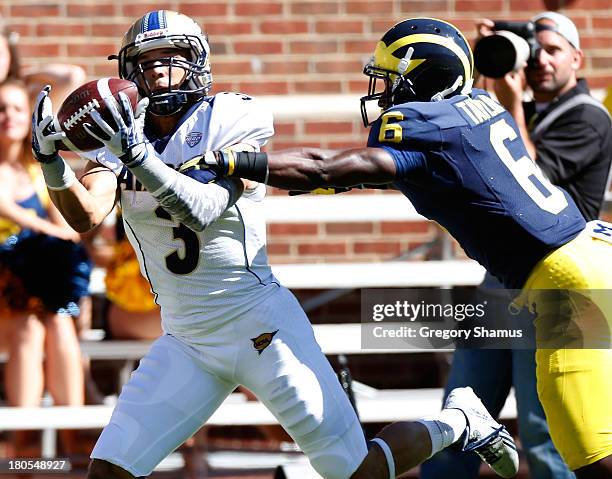 Smith of the Akron Zips makes a fourth quarter catch past the defense of Raymon Taylor of the Michigan Wolverines at Michigan Stadium on September...