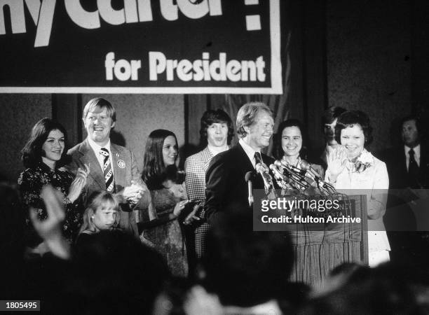 Democratic presidential candidate Jimmy Carter speaks at a podium while his brother Billy, wife Rosalynn and other family members applaud on election...