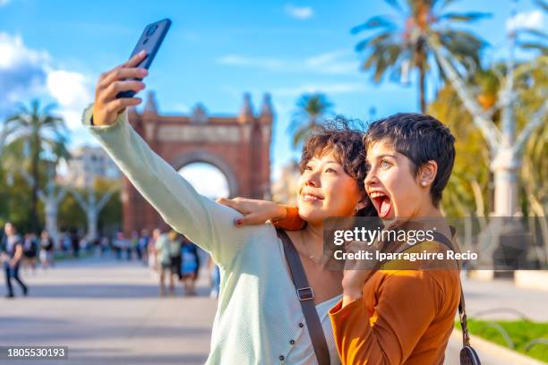 happy young multiethnic lesbian couple taking a selfie around the city and sightseeing on a sunny summer day - asian lesbians kiss stock pictures, royalty-free photos & images