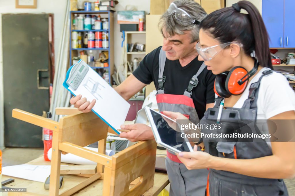A Group of Carpenters is Looking at the Tablet in a Workshop and Working on New Projects.