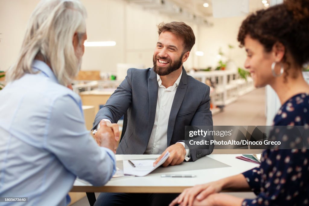 Real estate agent shaking hands with clients after signing contract
