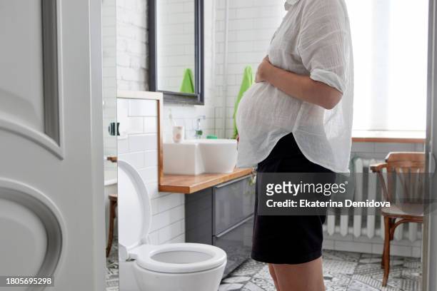 pregnant woman holding her belly in the toilet. delicate problems during pregnancy - people peeing 個照片及圖片檔