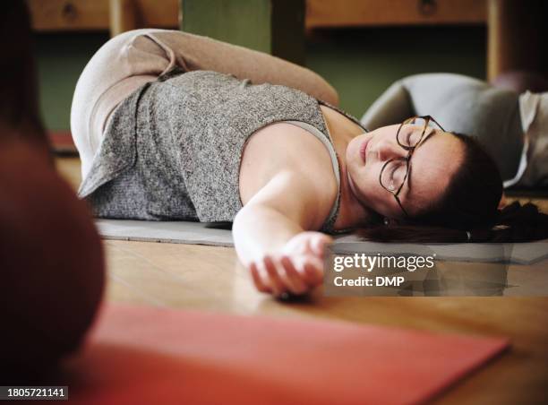 frau, yoga und unterricht auf der bodenmatte für bewegung, fitness oder workout in rückenlage wirbelsäulendrehung im fitnessstudio. ruhige weibliche person oder yogi in entspannung auf dem boden liegend für pilates, gesundheit und wellness zusammen - auf rücken liegen stock-fotos und bilder