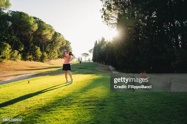 rear view of a lady golfer swinging club on the golf course - golfer swing stock pictures, royalty-free photos & images