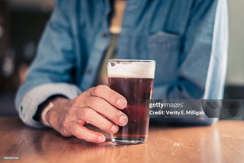 Older man holding glass for beer