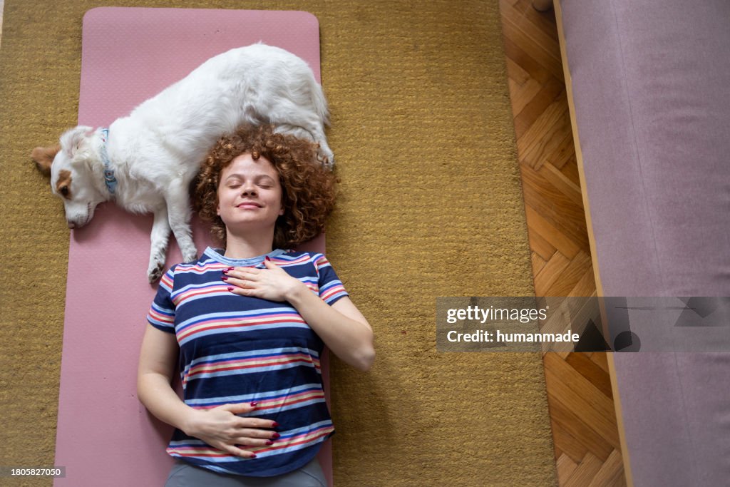 Top view of a woman cuddling with her dog on her yoga mat