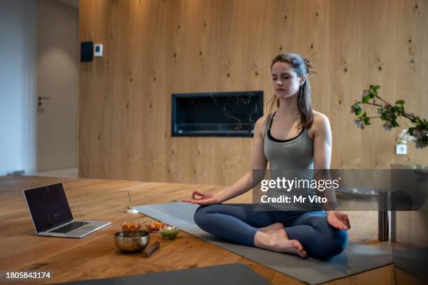 a young woman is learning yoga at home - siddhasana stockfoto's en -beelden