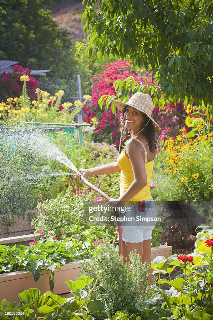 Young woman watering large vegetable garden