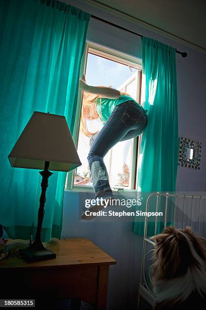 teen girl sneaking out her bedroom window - sneaking stock-fotos und bilder