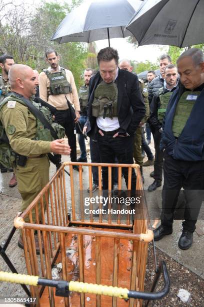 In this handout image provided by the GPO, Israel's Prime Minister Benjamin Netanyahu takes Elon Musk on a tour of Kibbutz Kfar Aza after the October...