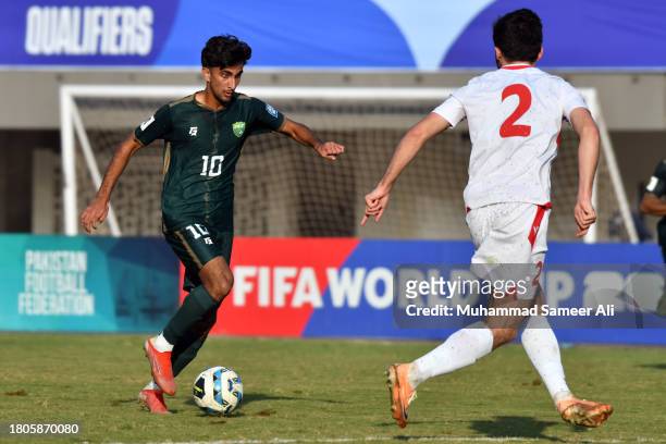 Muhammad Waleed Khan of Pakistan aims to pass through Zoir Dzhuraboev of Tajikistan during the 2026 FIFA World Cup AFC Qualifier Group G match...