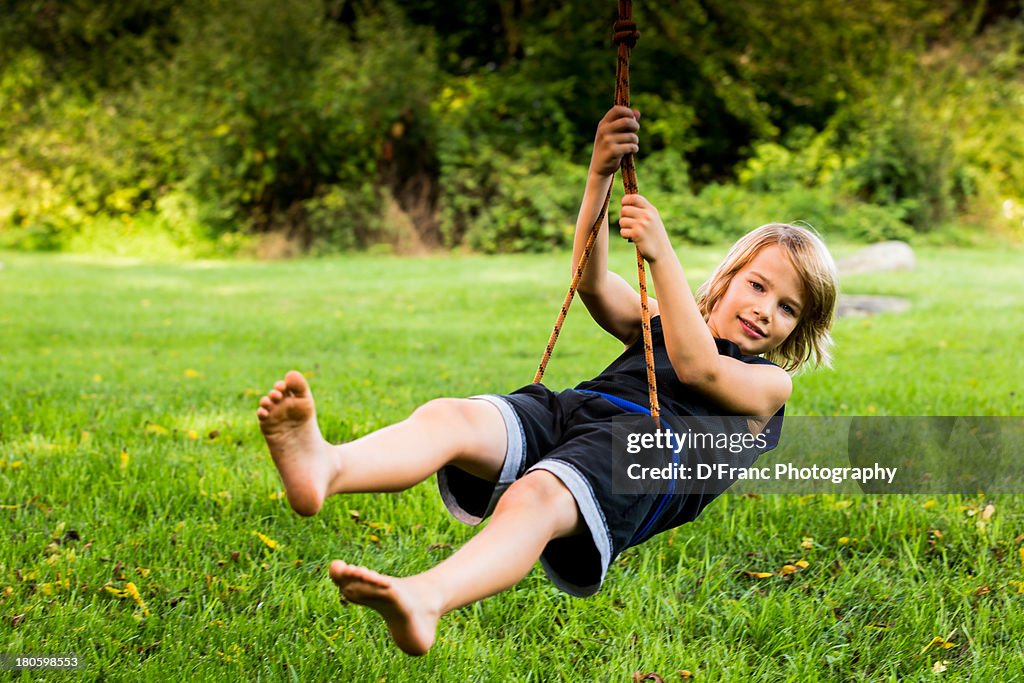 Blond barefoot boy on a rope swing