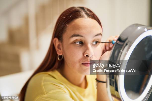 young girl putting on makeup using a brush to do her eyelashes - id de la fotografía foto e immagini stock