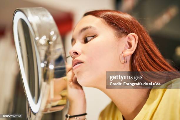 young girl putting on makeup using a brush to do her eyelashes - id de la fotografía foto e immagini stock