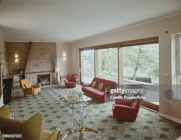 Interior view of a living room containing a sofa and armchairs, bare stone fireplace and chimney breast, television and coffee tables overlooking the...