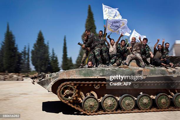 Members of rebel brigades parade on a tank during a ceremony to mark an agreement to unite the of forces Liwad al-Tawid and Liwaa al- Fatah brigades...