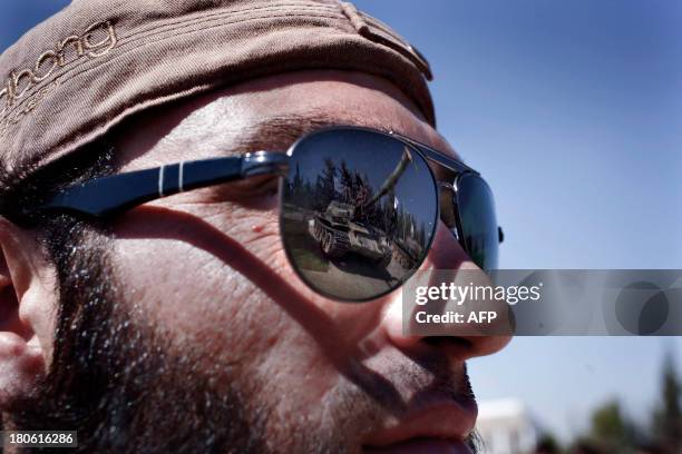 Tanks is reflected on the sunglasses of a rebel fighter during a ceremony to mark an agreement to unite the of forces Liwaa al-Tawid and Liwad al-...