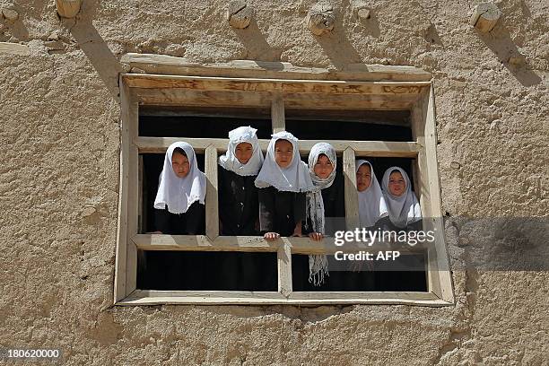 Afghan schoolgirls look on from a window of their school in Ghazni on September 15, 2013. Afghanistan has had only rare moments of peace over the...