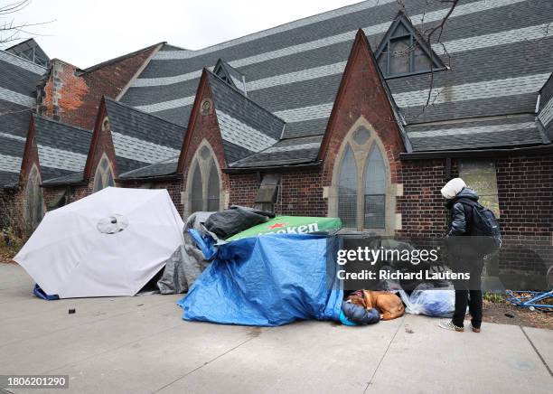 November 27 A passer-by checks in on a man who is sleeping in his tent with his dog out front along College street. A homeless encampment out front...