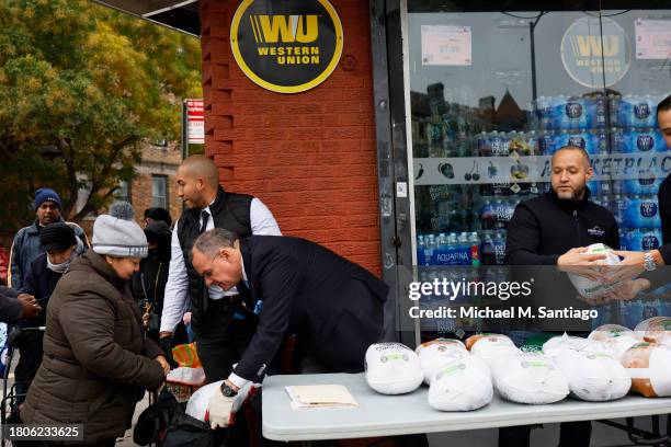 National Supermarket Association executive director Samuel Collado places a frozen turkey in a bag during a giveaway at Green Valley of Sunnyside...