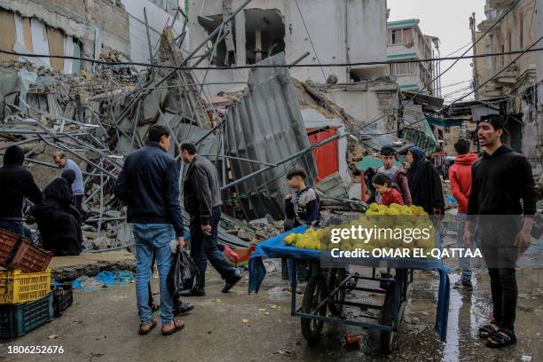 Palestinians sells vegetables amid debris of buildings hit in Israeli strikes, near Al-Zawiya market in Gaza City on November 27 on the fourth day of...