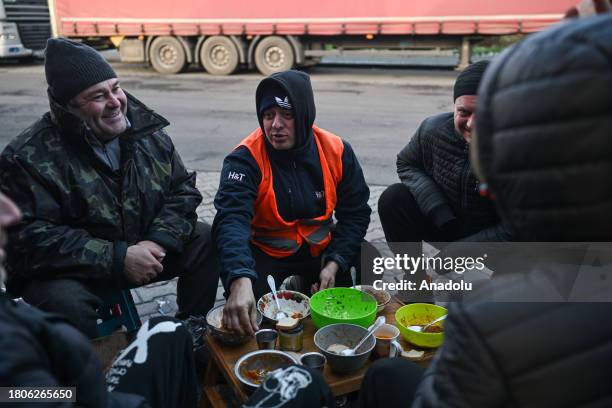 Ukrainian truck drivers seat around a small table to enjoy a meal together as they wait on a parking lot to cross the Polish blockade point in...