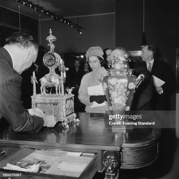 Queen Elizabeth II looks at an ornamental clock on display during a visit to the Victoria & Albert Museum, London, March 23rd 1962.