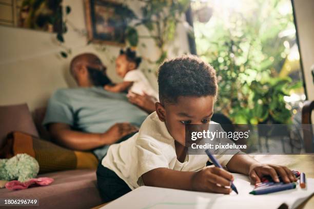 a relaxed dad multitasks with baby and child, fostering creativity and bonding in their warm, inviting living space - day in the life series stock pictures, royalty-free photos & images