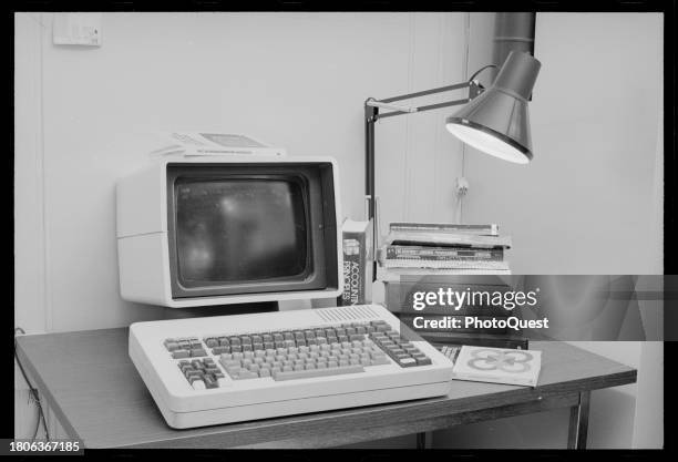 View of monitor and computer keyboard beside a stack of books and desk lamp, Washington DC, August 22, 1982. Among the books are 'The Z-80...