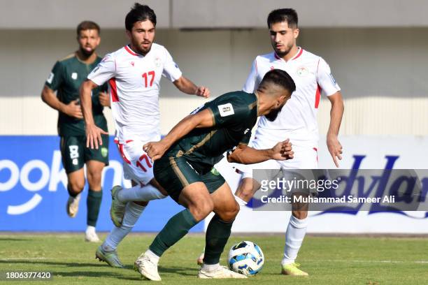 Ehson Panshanbe and Rustam Soirov of Tajikistan chase for the ball against Mamoon Moosa Khan of Pakistan during the 2026 FIFA World Cup AFC Qualifier...