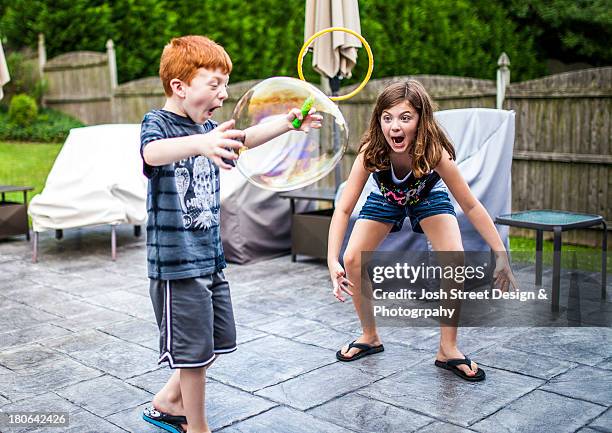 young children blowing large bubbles - kid in big shoes stock pictures, royalty-free photos & images