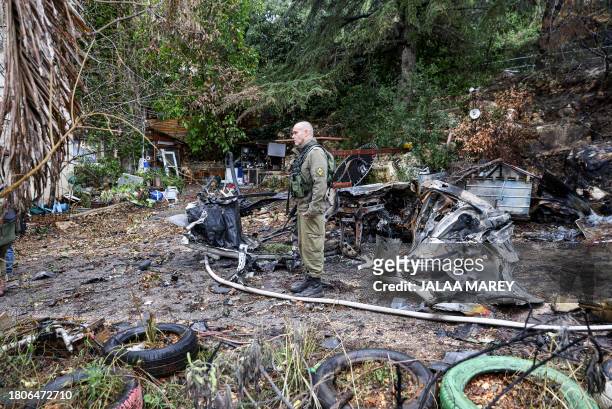Soldier stands near a car destroyed in a strike by Lebanon's Hezbollah movement in Kibbutz Manara in northern Israel near the Lebanon border, on...