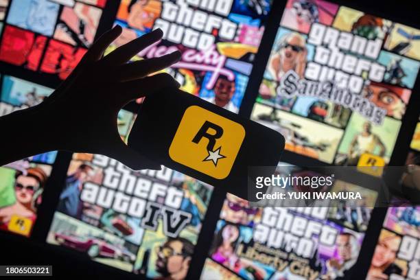 This illusttation shows a logo of Rockstar Games on a smartphone screen and covers of video game series Grand Theft Auto on a TV screen in New York,...