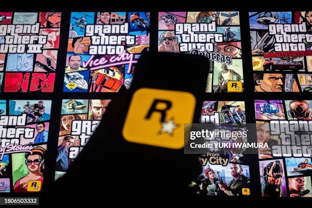This illusttation shows a logo of Rockstar Games on a smartphone screen and covers of video game series Grand Theft Auto on a TV screen in New York,...