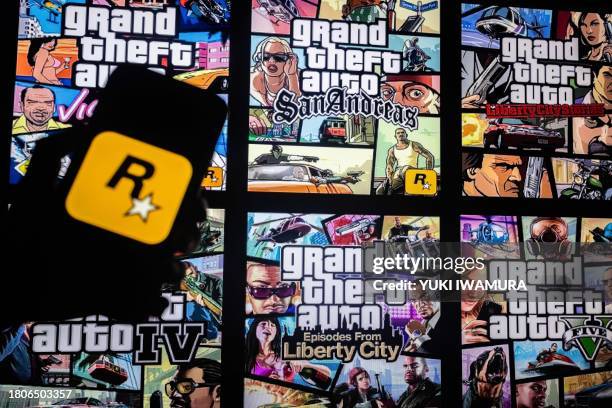 This illusttation shows a logo of Rockstar Games on a smartphone screen and covers of video game series Grand Theft Auto on a TV screen in New York,...