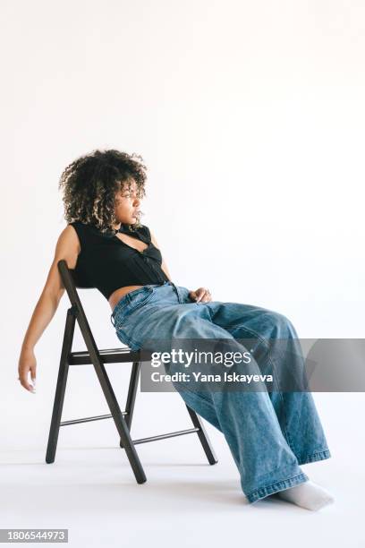 a beautiful young woman posing on the chair in a white studio - actress icon stock pictures, royalty-free photos & images