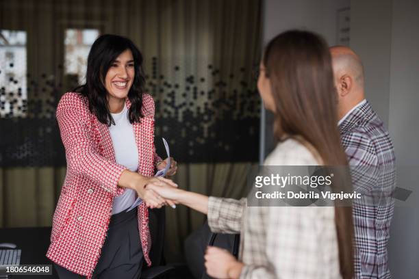 businesswoman shaking hands with business partners - employee wellbeing stock pictures, royalty-free photos & images